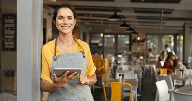 small business owner smiles towards the camera holding a tablet