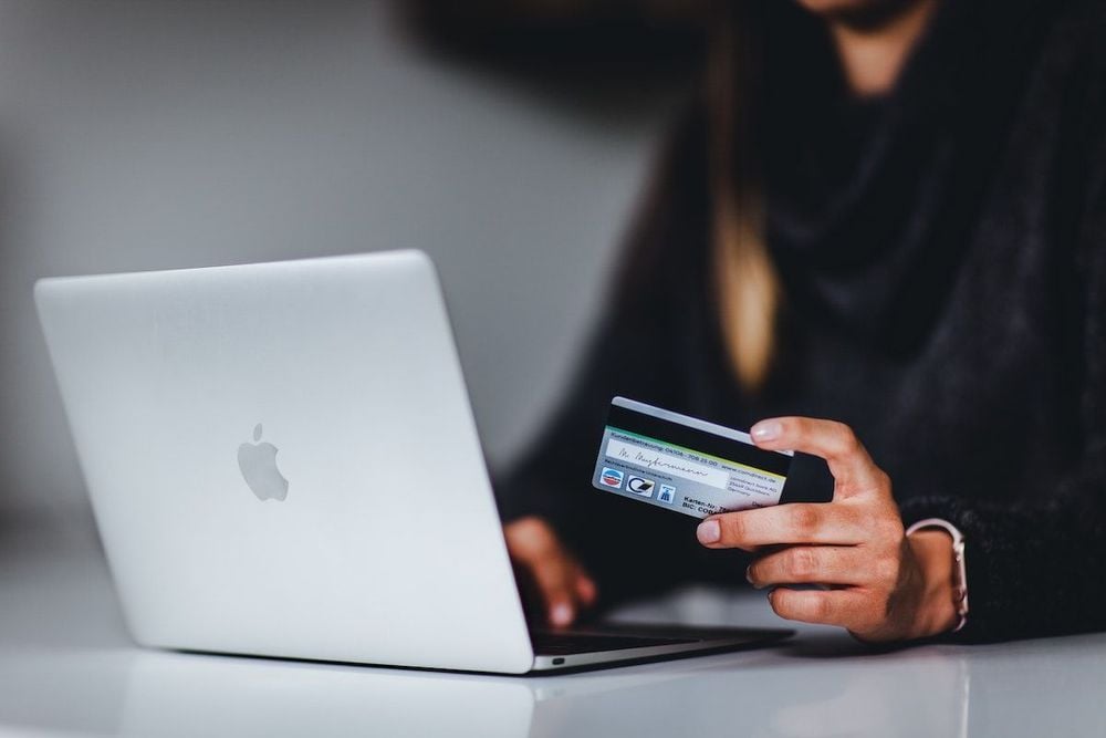 person holding direct debit card in front of laptop